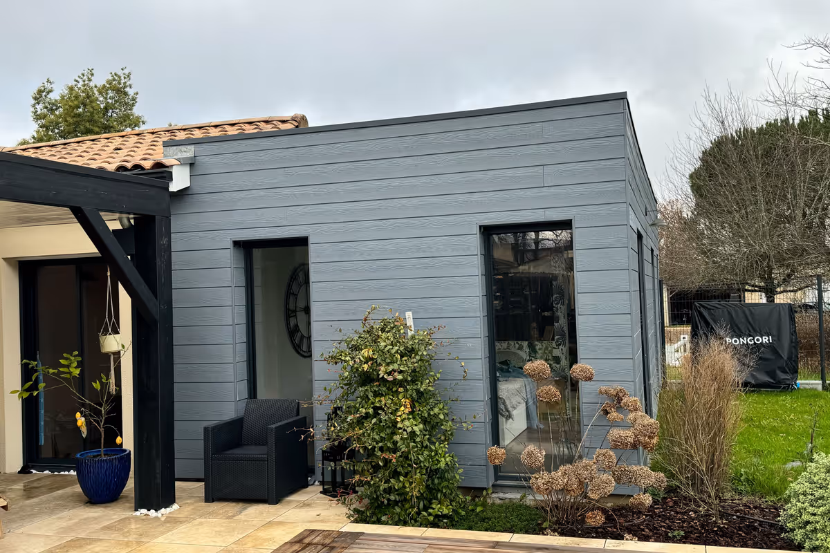 Extension bois à toit plat livrée à Libourne, bardage gris horizontal et acrotère masquant la toiture