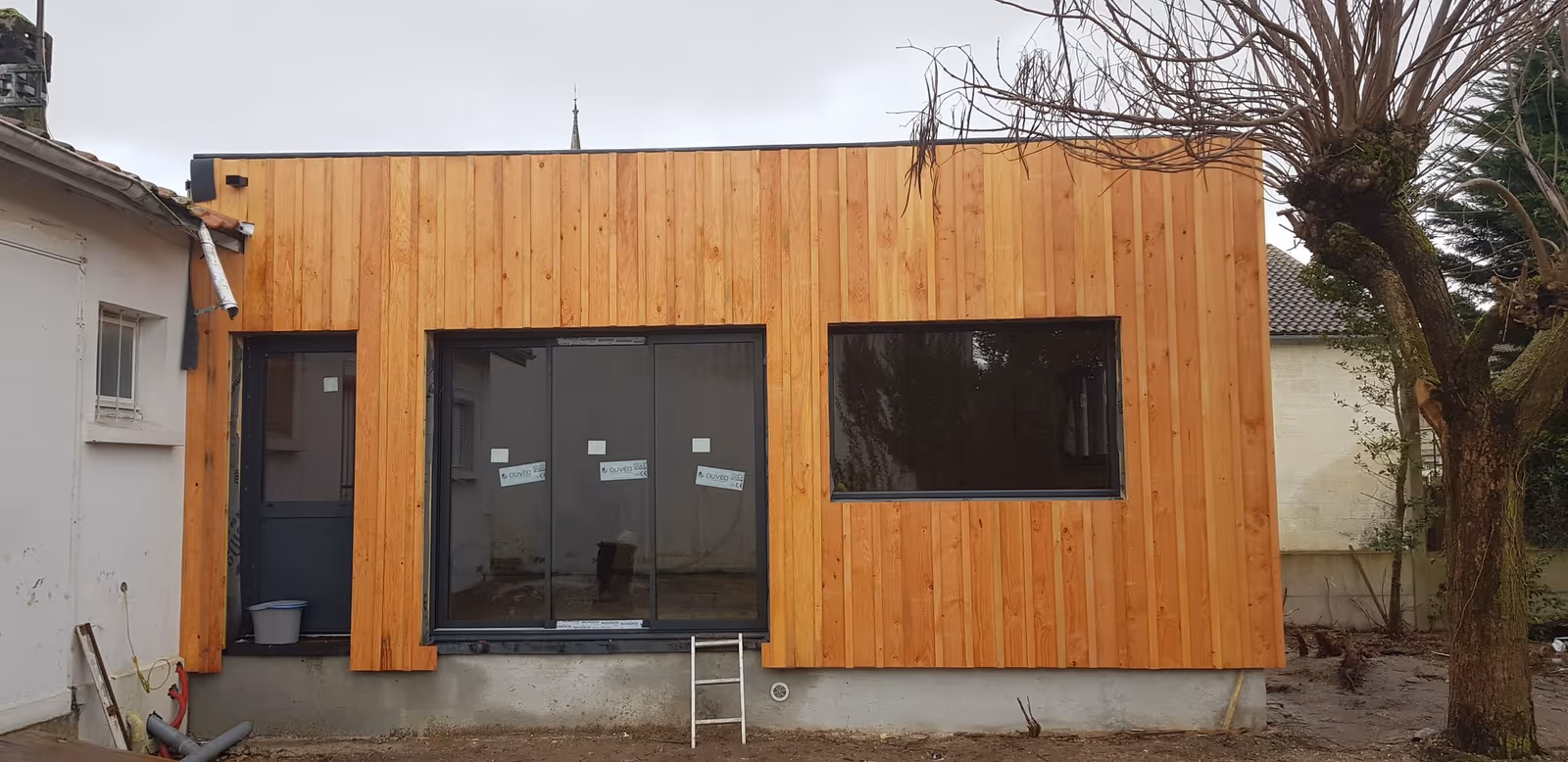 Extension à toit plat en ossature bois avec bardage bois vertical, chantier à Bordeaux