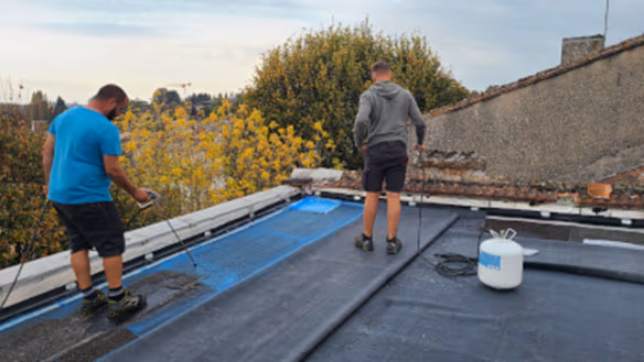 Application de la colle pulvérisée sur une ancienne étanchéité bitume avant déroulage de la membrane EPDM