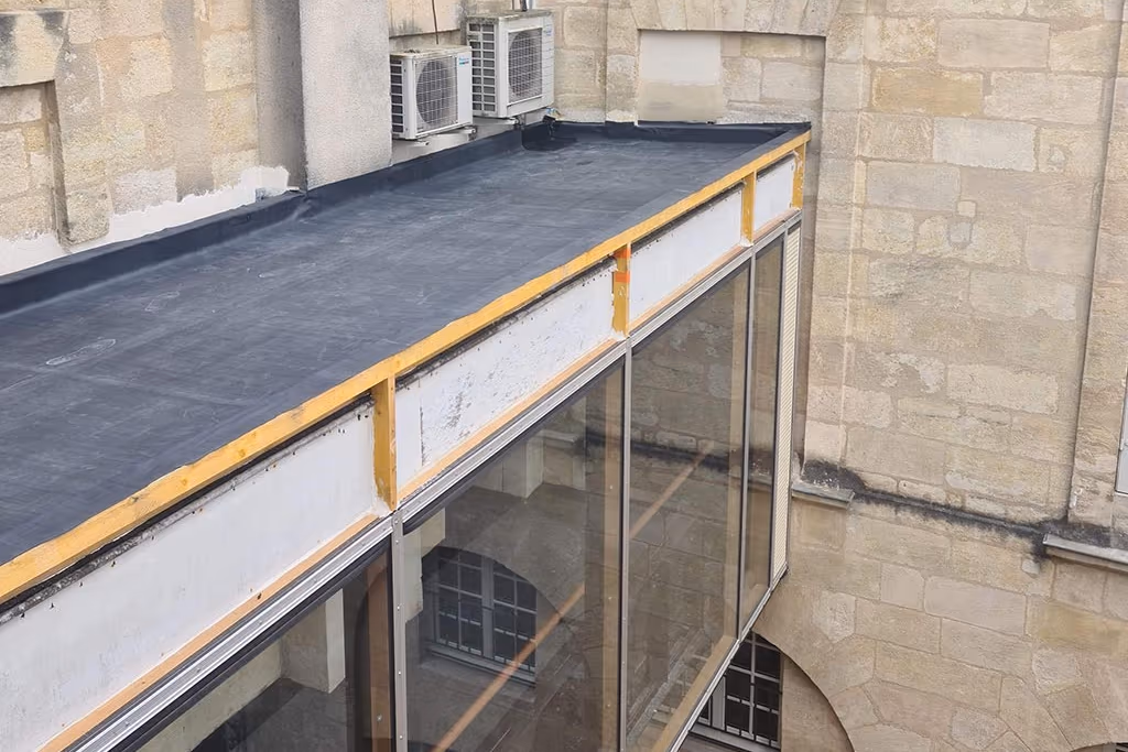 Membrane EPDM déroulée sur une toiture d'immeuble bordelais, relevé contre le mur en pierre et rive périphérique
