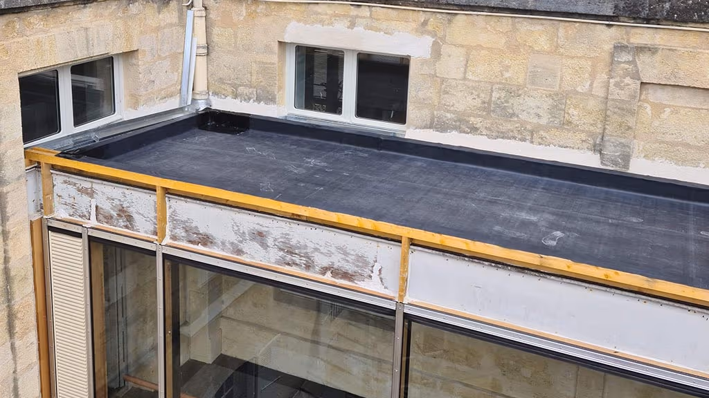 Membrane EPDM posée sur la toiture d'une galerie vitrée à Bordeaux, relevés contre la façade en pierre