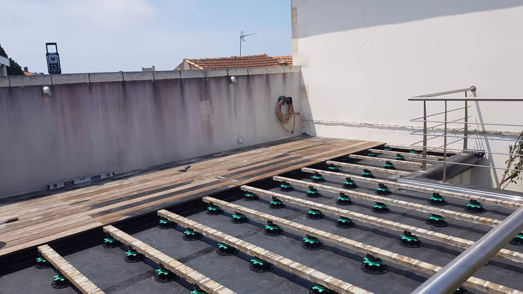 Plots réglables à embase large et lambourdes posés sur la toiture de Fouras, platelage bois en cours de pose